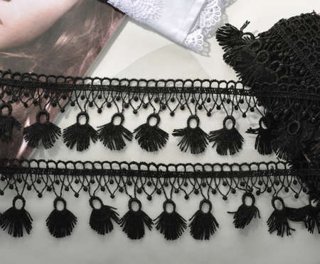 Tapes of black gentle guipure, beauty lace fabric on light background. Elastic material. Using for...