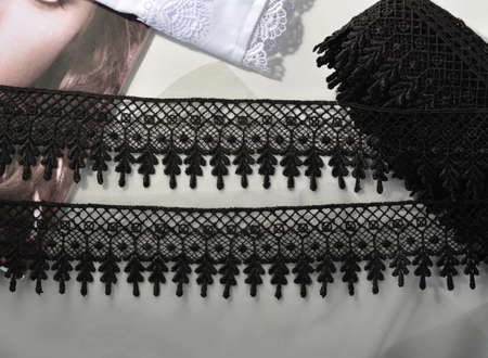 Tapes of black gentle guipure, beauty lace fabric on light background. Elastic material. Using for...