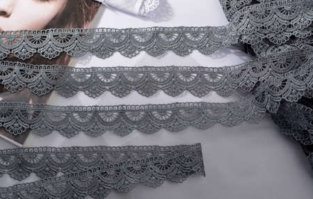 Tapes of gray gentle guipure, beauty lace fabric on light background. Elastic material. Using for...
