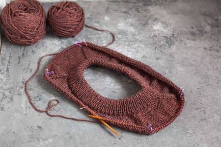 Brown sweater, knitting process, concrete background. Raglan needles. woolen weave threads.