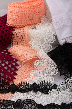 pile of orange, red, white. and black gentle luxury quality guipure, lace fabric. use for sew...