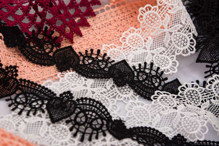 pile of orange, red, white. and black gentle luxury quality guipure, lace fabric. use for sew...
