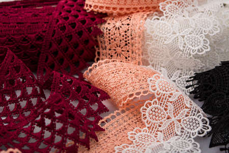 pile of orange, red, white. and black gentle luxury quality guipure, lace fabric. use for sew...