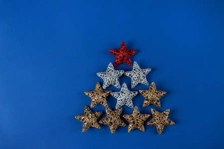 Brilliant red, gold, silver Christmas star on blue background. Use for New Year's greetings. Minimal...