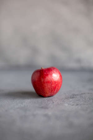 one Ripe garden red apples on gray concrete. Fruits concept of the fall harvest. Space for text. Selective soft focus.の写真素材