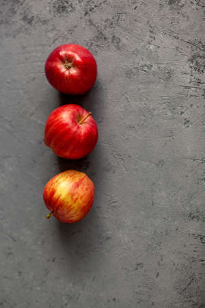 Three Ripe garden red apples on gray concrete. Fruits concept of the fall harvest. Space for text.の写真素材