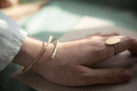 sophisticated female hand with Hammered brass Copper ethnic bracelet and gold vintage stylish polished ring. Ancient times type jewelry accessories concept. Selective soft focusの写真素材