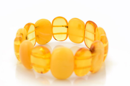 Bracelet made of Natural polished transparent honey luxury amber beads with inclusions on white. close up selective soft focus. Space for textの写真素材