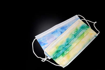 Art blue green Medical surgical disposable medical protective face mask on a black background. Antivirus, three Ply Disposable, Mouth Anti Dust Fog Facial Nonwoven Protective. Epidemic Concept.の写真素材