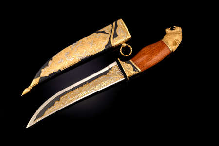 souvenir collectible silver gold dagger cutlass with scabbard, with metal engraving, on black background. Luxury weapons with traditional patterns in medieval vintage style.の写真素材