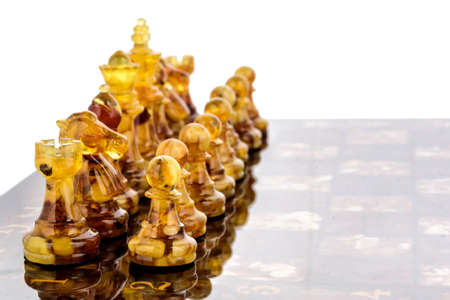 Natural amber different chess pieces figures standing on lacquer surface board on white. Close up game concept competition, Classic Tournament of confrontation.の写真素材