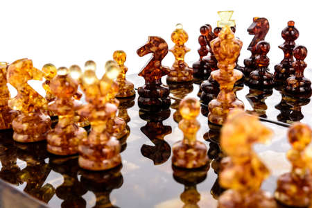 Natural amber different chess pieces figures standing on lacquer surface board on white. Close up game concept competition, Classic Tournament of confrontation.の写真素材