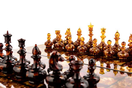 Natural amber different chess pieces figures standing on lacquer surface board on white. Close up game concept competition, Classic Tournament of confrontation.の写真素材