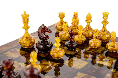 Natural amber different chess pieces figures standing on lacquer surface board on white. Close up game concept competition, Classic Tournament of confrontation.の写真素材