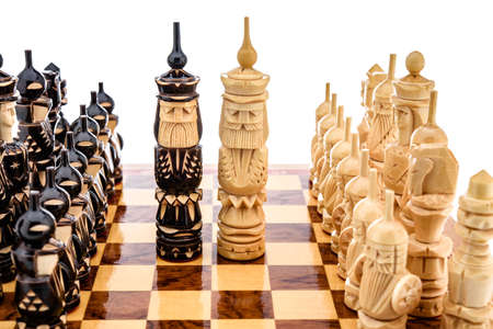 Beige Brown Wooden chess different pieces figures with carving standing on chessboard. Closeup game...