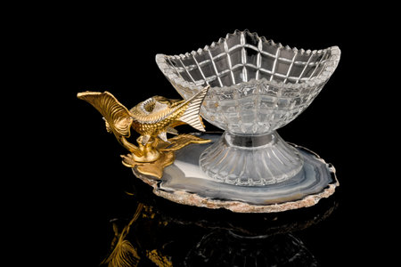 Gilded luxury crystal caviar bowl on stand made of natural quartz, carved brass fish figurine on a black background.の写真素材