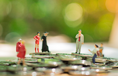 Miniature people: small figures businessmen stand on top of coins. Business Growth concept.の写真素材
