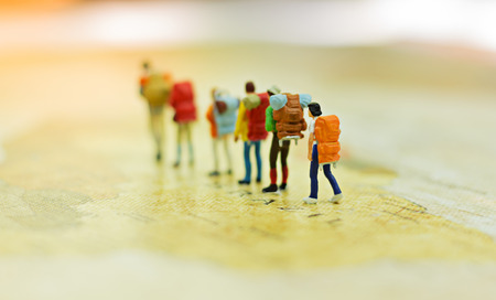Miniature people, travelers with backpack standing on world map, walking to destinationの写真素材