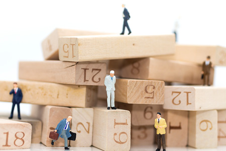 Miniature people : Businessmen standing in various positions of wooden numbers, indicating the...