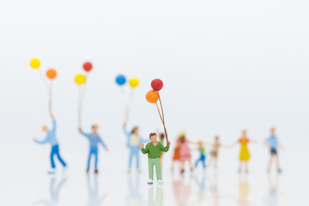 Miniature people: children hold balloons, and play together, using as background International day of families concept.の写真素材
