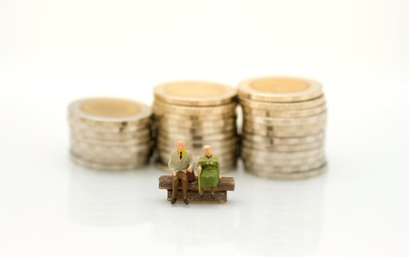 Miniature people, Old couple figure sitting on the chair with  stack of coins. Image use for background retirement planning, Life insurance concept.の写真素材