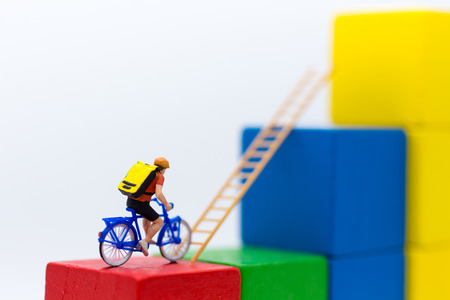 Miniature people : Traveler use the bicycle with takes the ladder from one place to another. Image use for travel, business concept.の写真素材