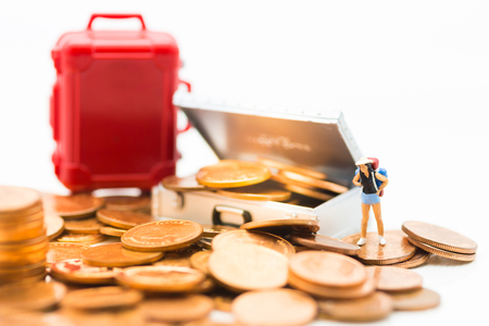 Miniature people : Tourist stand on a pile of coins and have a red suitcase. Image use for travel, business concept.の写真素材