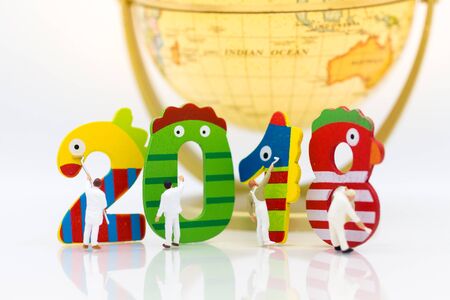 Miniature people: Group Worker painting wood color number 2018 with workd map. Image use for background new year, business concept.の写真素材