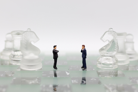 Miniature people, Businessmen stand on opposite sides of the chess game, separate party , benefit, use as a business competition concept.の写真素材