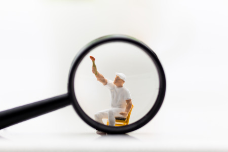 Miniature people: Worker are wiping the glass of a magnifying glass. Image use for background business concept.の写真素材
