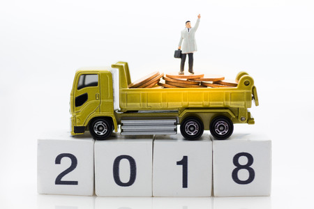 Miniature people: Businessman standing on stack of coins with truck. Image use for background...
