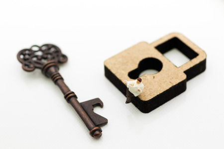 Miniature people: Businessmen sitting on the master key and reading newspaper. Image use for key man, the key to success, business concept.の写真素材