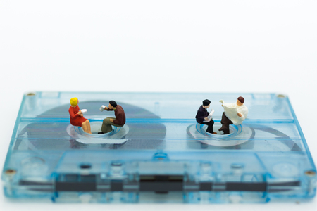 Miniature people: Businessman sit and reading newspaper  on Compact Cassette. Image use for music , business concept.の写真素材