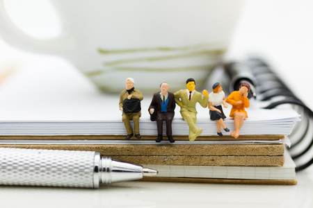 Miniature people : Business team sitting on book and having a coffee break. Image use for business concept.の写真素材