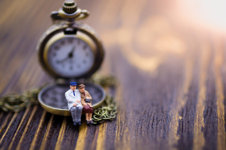 Miniature people: Old couples are sitting on the clock. Image use for spending precious minutes every minute together.の写真素材
