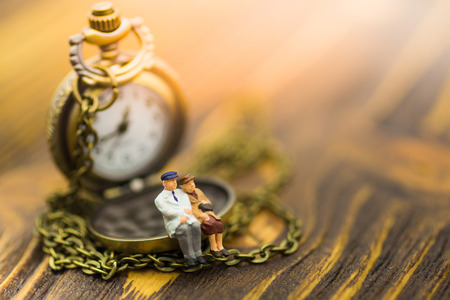 Miniature people: Old couples are sitting on the clock. Image use for spending precious minutes...