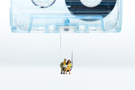 Miniature people: Couple sit on line inside Compact Cassette. Image use for love song, music, business concept.の写真素材