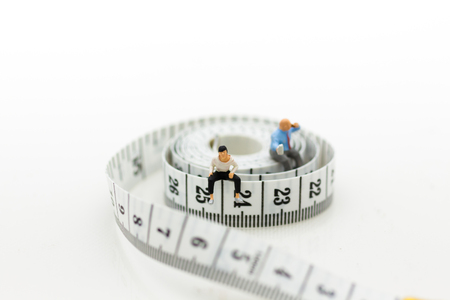Miniature people: Man and woman sitting on the waistline and drinking coffee. Image use for health concept, take care yourself, exercise.の写真素材