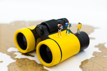Miniature people: Travelers standing on a world map with binoculars. Image use for travel , business concept.の写真素材