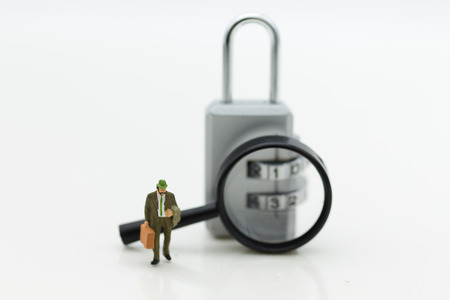 Miniature people:  Businessman with a magnifying glass and master key encoding. Image use for background security system, hack, business concept.の写真素材