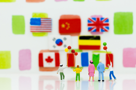 Miniature people: family group standing with flag international for background. Image use for learning, education concept.の写真素材