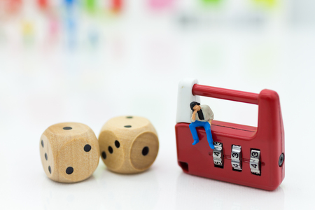 Miniature people:  businessman sitting on security key and dice . Image use for background security system, hack, business concept.の写真素材