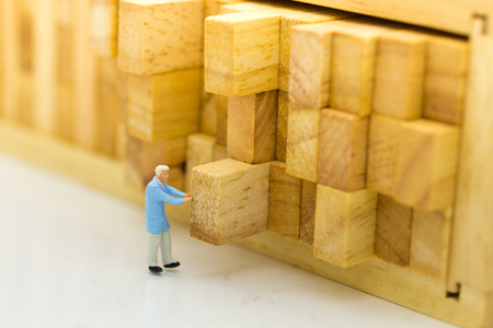 Miniature people : Worker push the wood log back into place. Image use for allocating space to stock, warehouse, business concept.の写真素材