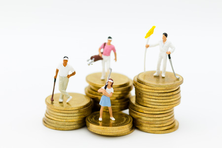 Miniature people: Golfers standing on coins. Image use for . Image use for sport,activities , hobbies concept.の写真素材