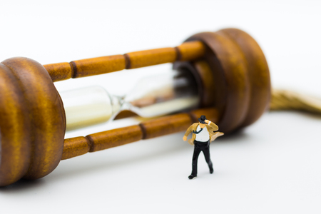 Miniature people : businessman and Tie blowing in wind with hourglass. Image use for business concept.の写真素材