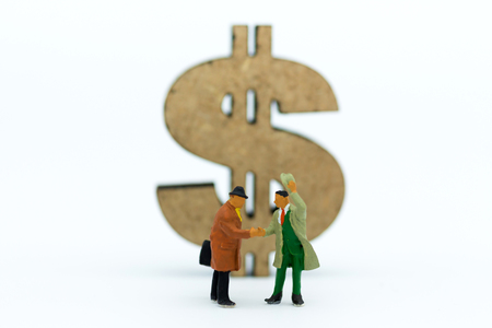Miniature people : Two businessmen make a deal, with currency to background. Image use for commitment, finance, investment and partnership concept.の写真素材
