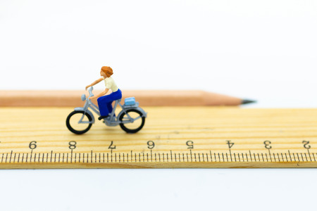 Miniature people: Women cycling  on ruler. Image use for travel, business concept.