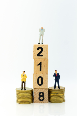 Miniature people: Businessman standing with stack of coins and wooden block 2018. Image use for investment for benefit of year, business concept.の写真素材