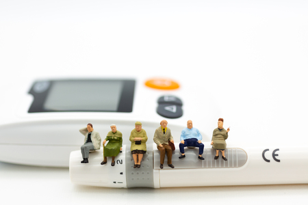 Miniature people sitting on glucose meter with lancet. Image use for medicine, diabetes, health care concept.の写真素材