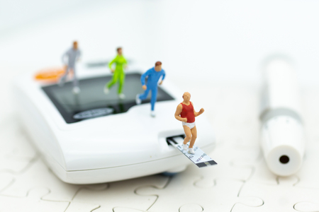 Miniature people exercise running on glucose meter with lancet. Image use for medicine, diabetes, health care concept.の写真素材